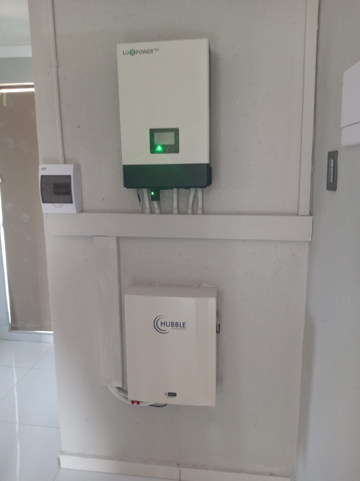 LuxpowerTek smart hybrid inverter wall-mounted above a Hubble Lithium battery — residential hybrid solar installation Gauteng