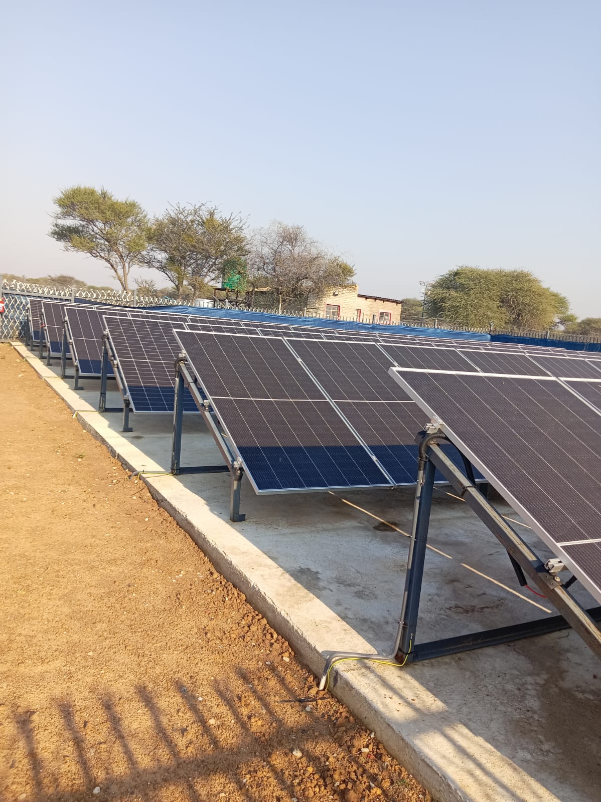 Close-up ground-mounted solar PV array — rows of polycrystalline panels on steel racking with concrete footings in a Gauteng commercial site